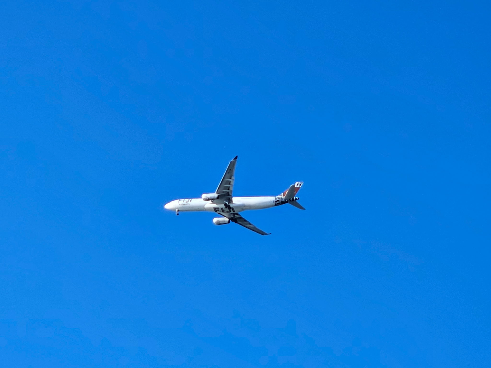 Fiji Airways airplane flying through a vivid blue sky